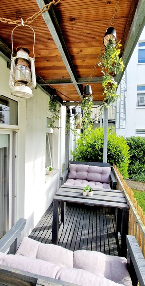 Relax on the outdoor patio with a wooden deck and seating, surrounded by lush greenery and a scenic view.