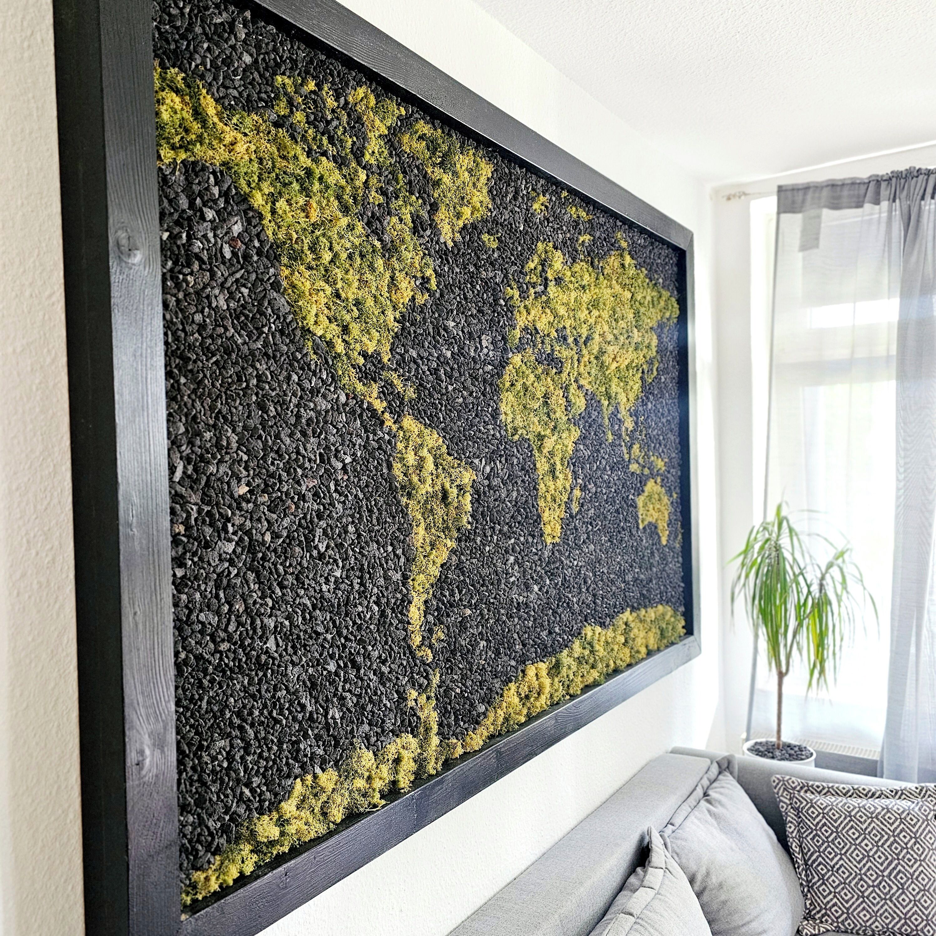 Grande obra de arte abstrata com design de mapa-múndi, fixada numa parede acima de um sofá cinza com almofadas estampadas.