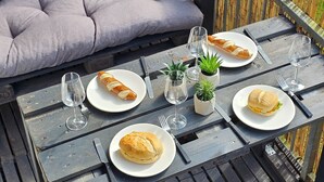 A dining table set with plates, glasses, and a baguette. - The World Appartment (Magdeburg)