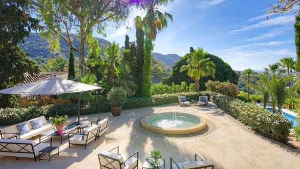 Eine Terrasse mit Gartenmöbeln, einem Brunnen und einem Pool.