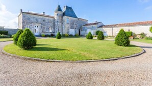 A historic building with a central tower, surrounded by a well-maintained lawn and gravel paths. - Chateau Serbise Estate (Belluire)