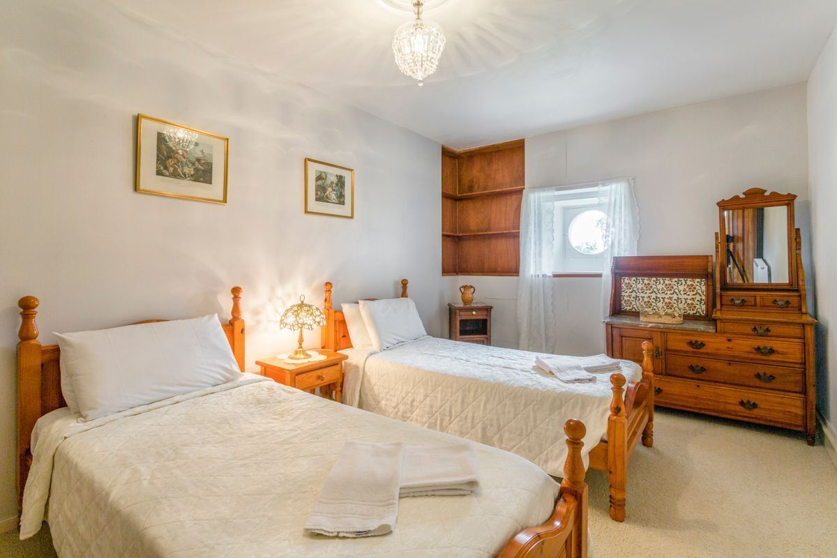 Een slaapkamer met twee houten bedden, een houten dressoir en een kroonluchter.