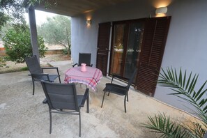 Enjoy al fresco dining on this patio with a table and chairs, surrounded by lush greenery.