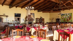 A restaurant with wooden beams, red tablecloths, and a stone fireplace. - Agriturismo nel cuore del Pollino - Matrimoniale (Plataci)