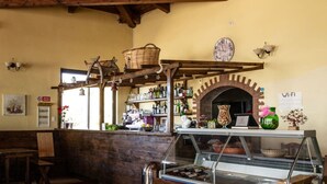 A rustic interior with wooden beams, a brick fireplace, and a glass display case. - Agriturismo nel cuore del Pollino - Matrimoniale (Plataci)