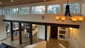 Un loft espacioso con techo alto, ventanas grandes que ofrecen vistas a árboles, un comedor y una cocina.