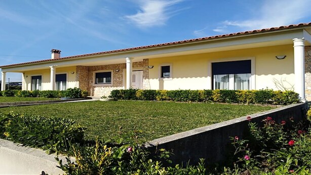 A two-story house with a tiled roof, a front porch, and a well-maintained lawn. - Casa Rural Muito Tranquila (Ortigosa de Cima)