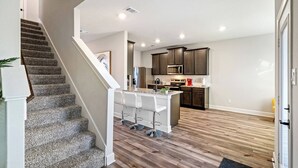 Une cuisine moderne avec des meubles en bois foncé, des appareils en acier inoxydable et un îlot central doté de tabourets de bar.