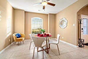 Cozy dining area with a round table and four chairs, complete with a ceiling fan and large window.