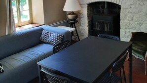 Un salon chaleureux avec une cheminée en pierre, un canapé agrémenté de coussins à motifs, une table et une lampe.