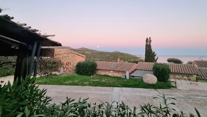 A residential area with stone buildings, a paved road, and a view of the sea. - Moon House 350mt from the beach Sea view Garden Free private parking  (Villasimius)