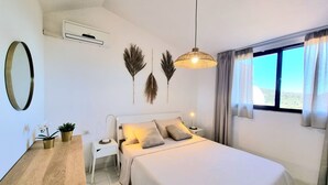 A bedroom with a bed, bedside tables, a mirror, and a window with curtains. - Moon House 350mt from the beach Sea view Garden Free private parking  (Villasimius)
