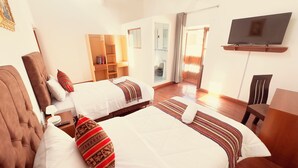 Habitación de hotel con dos camas, televisión, armario y baño visible a través de una puerta abierta.