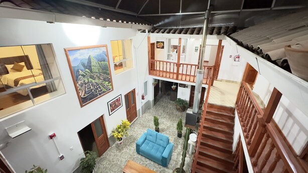 Un interior amplio con un sofá azul, una escalera y un balcón.