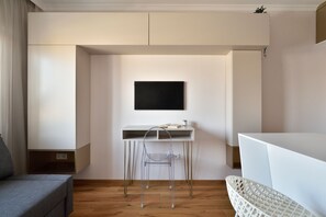 A modern room with a white desk, a clear chair, a flat-screen TV, and a grey sofa. - Warszawianka Studio (Warsaw)