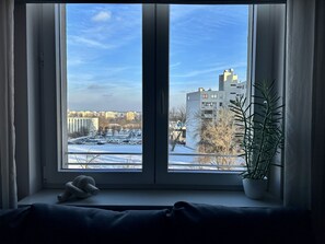 A room with a large window overlooking a snowy landscape and buildings. - Warszawianka Studio (Warsaw)