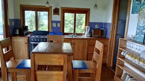 Una cocina con mobiliario de madera, estufa a gas y cafetera.