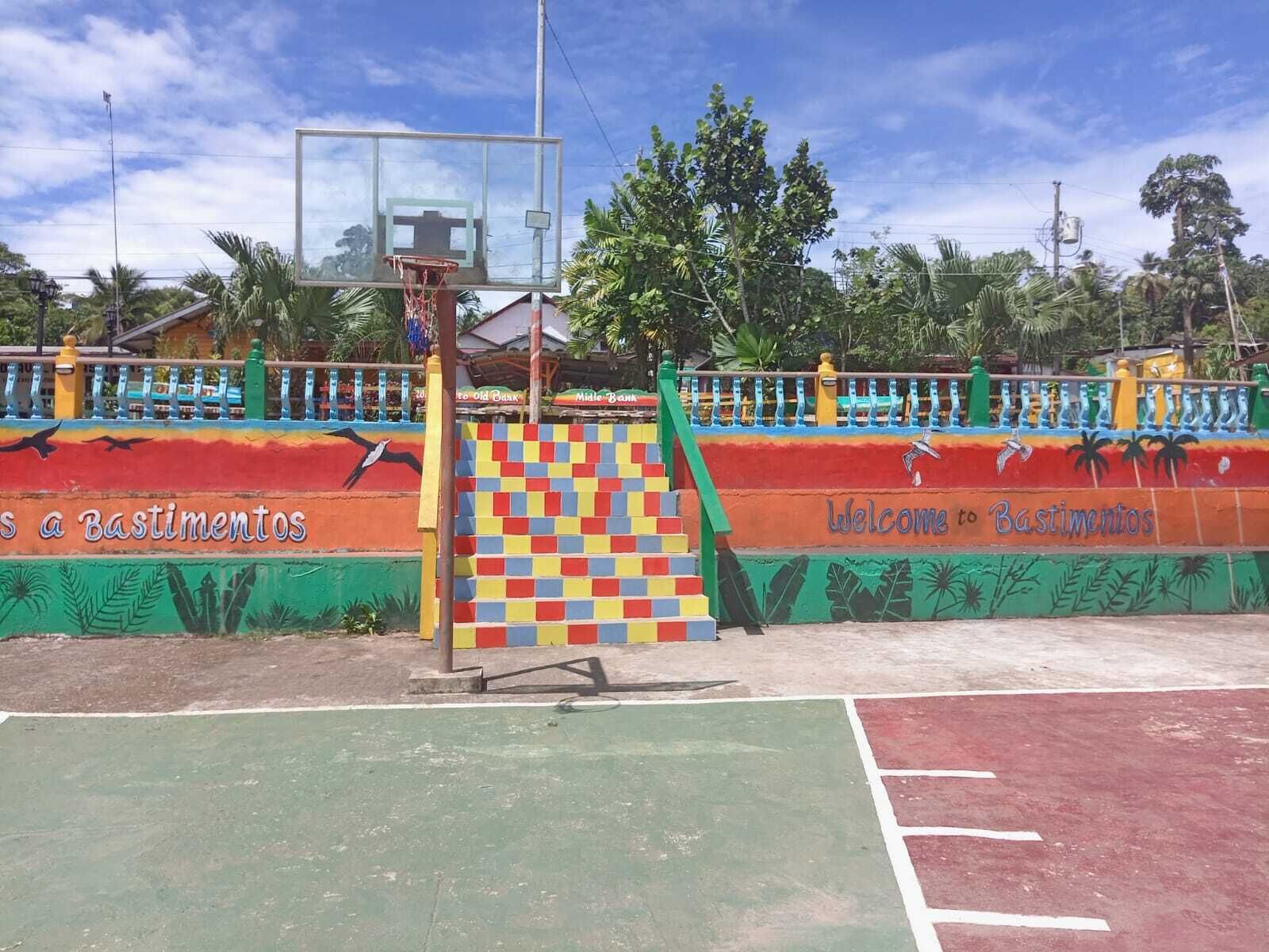 A basketball court with a colorful fence and a basketball hoop.