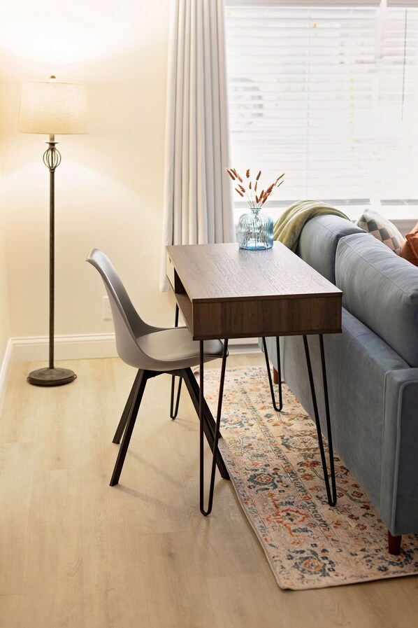A modern living room with a wooden coffee table, a grey chair, a floor lamp, and a blue sofa. - Homey Haven in Tower Grove Near Major Hospitals
(St. Louis)
