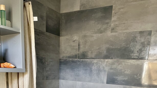A bathroom with a bathtub, a toilet, and a shelf with toiletries. - Stylish, dog friendly, recently renovated home <3 miles from Texas A&M. 
 (Bryan)