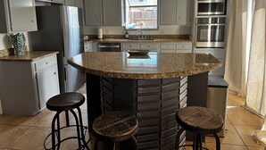 A kitchen with granite countertops, a central island with stools, stainless steel appliances, and a window with a view. - Stylish, dog friendly, recently renovated home <3 miles from Texas A&M. 
 (Bryan)