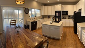 A modern kitchen with white cabinetry, a wooden dining table, and a built-in island.