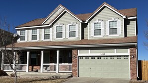 A two-story house with a garage, a covered porch, and a brick facade.