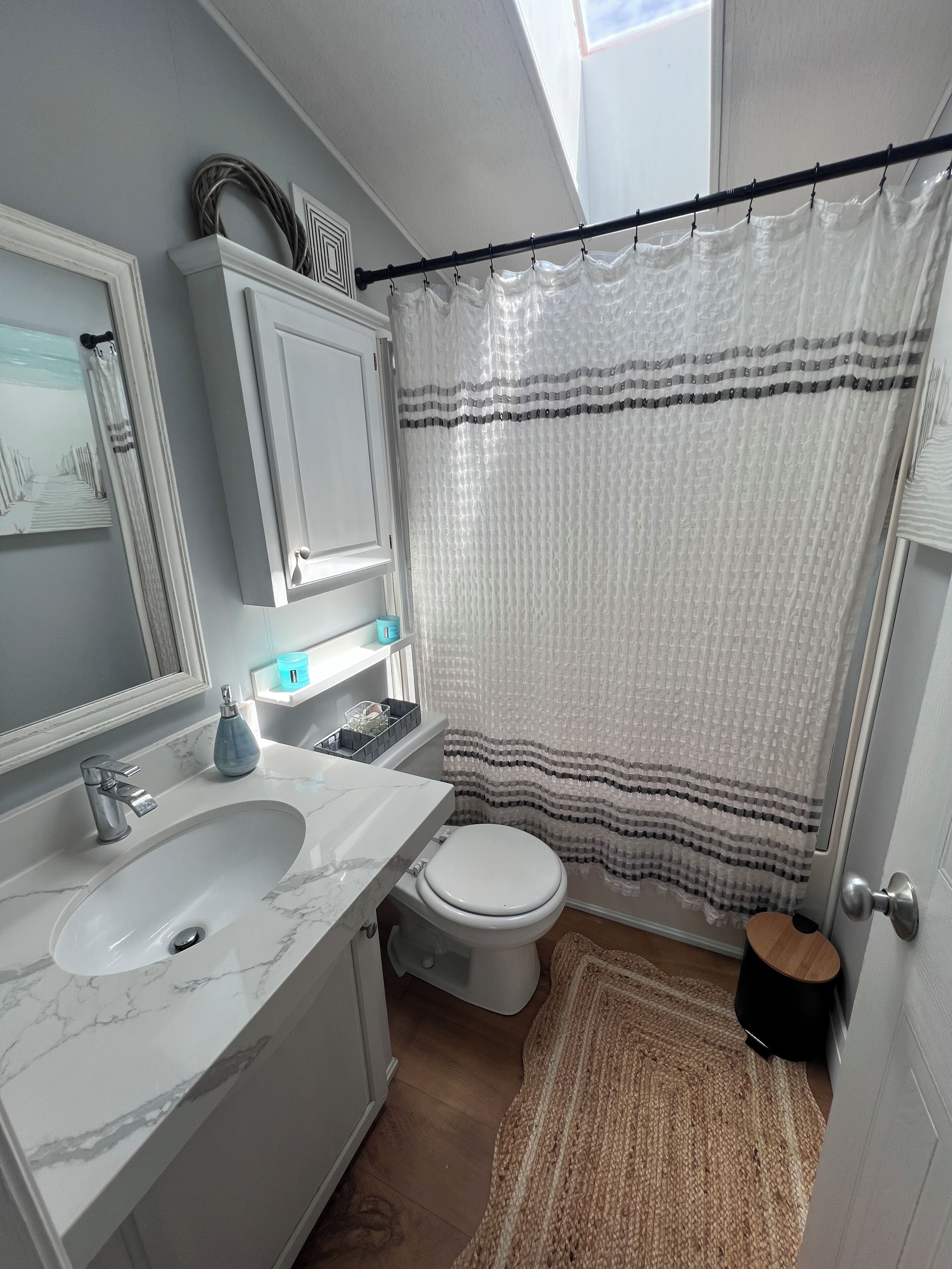 A bathroom with a white sink, toilet, and shower curtain.