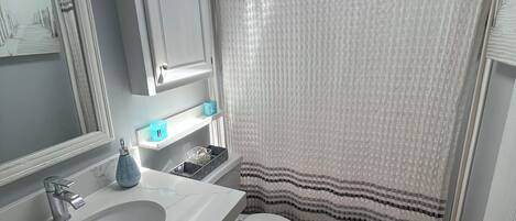 A bathroom with a white sink, toilet, and shower curtain.