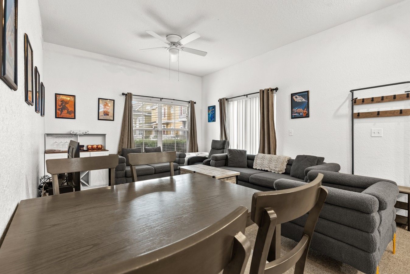 Een moderne woonkamer met een eettafel, banken en een plafondventilator.