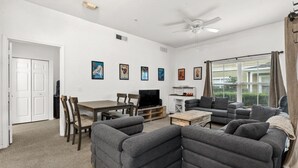Ein Wohnzimmer mit einer Sofagarnitur, einem Fernseher, einem Deckenventilator und gerahmten Kunstwerken an der Wand.