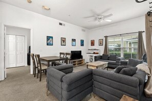A living room with a sofa set, a TV, a ceiling fan, and framed artwork on the wall. - Beautiful Florida Condo  (Kissimmee)