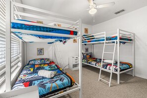 A bunk bed room with a ceiling fan, a window with blinds, and a small bedside table. - Beautiful Florida Condo  (Kissimmee)