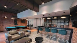 A lounge area with a pool table, leather sofas, and a patterned floor.