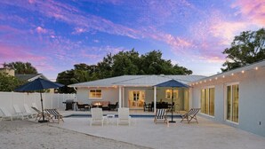 Een huis met een overdekte patio, buitenmeubels en een zwembad.