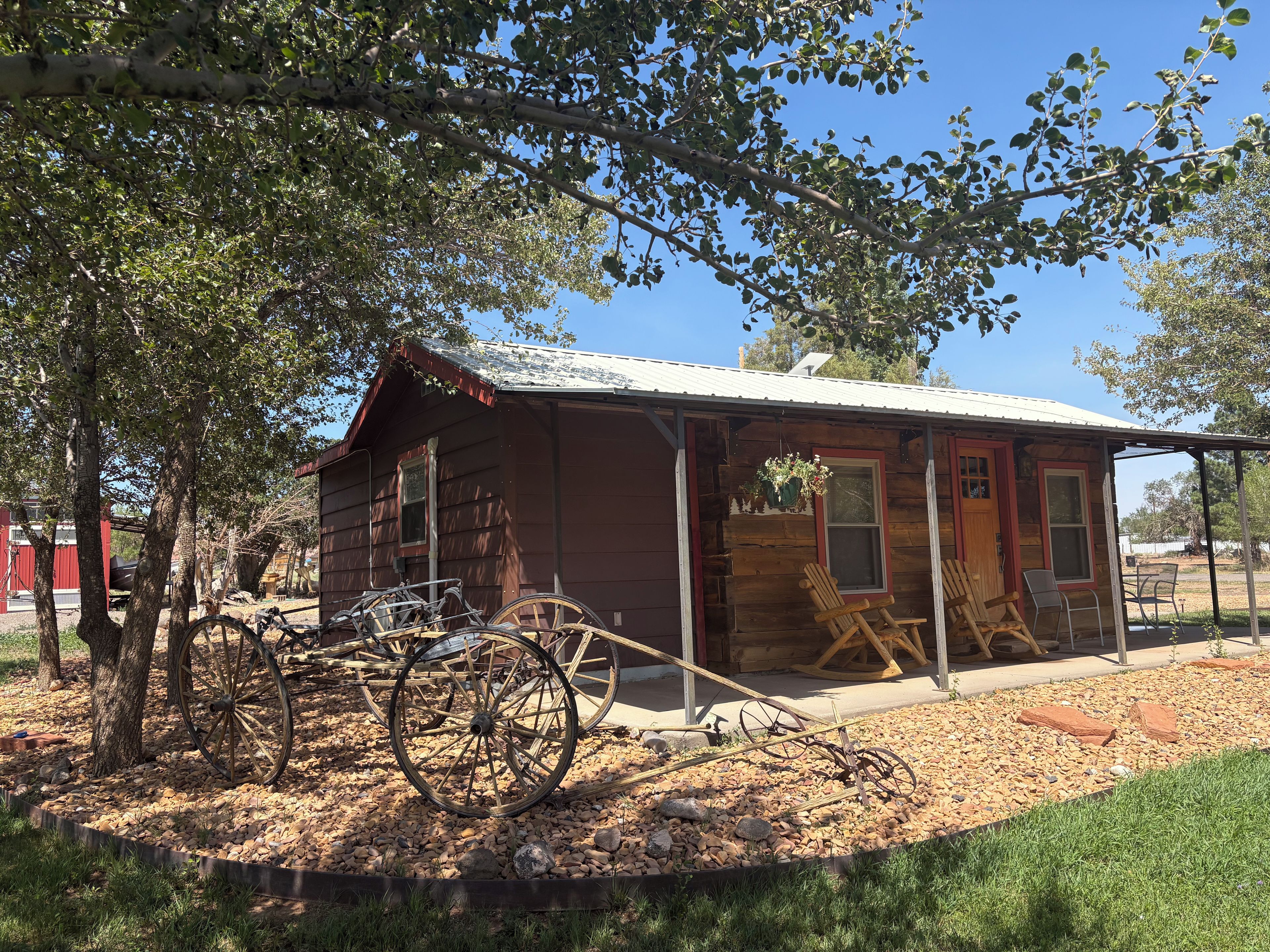 A rustic wooden cabin with a porch, a bicycle, and a wagon wheel.