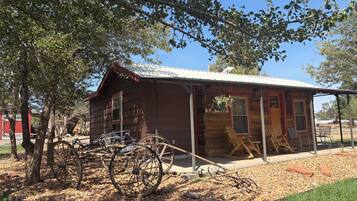 A rustic wooden cabin with a porch, a bicycle, and a wagon wheel.
