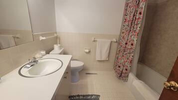Un baño con lavamanos, inodoro y cortina de ducha blancos.