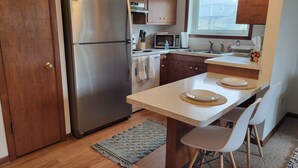 Une cuisine compacte avec des meubles en bois, un réfrigérateur en acier inoxydable, un four à micro-ondes et une petite fenêtre.