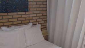 Ein Bett mit weißer Bettwäsche vor einer Ziegelwand.