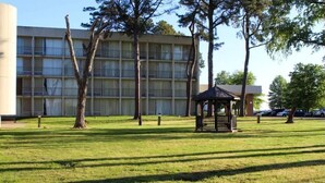 A grassy area with a gazebo and a building with multiple windows in the background. - Home Inn Woods Hotel (Olive Branch)