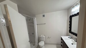 A bathroom with a shower, toilet, sink, and mirror. - Home Inn Woods Hotel (Olive Branch)