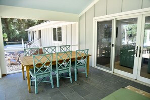 A covered patio area with a wooden table and matching chairs, a sliding glass door, and a view of outdoor seating. - Pet-Friendly Waterfront Retreat w/ Private Dock on Virginia’s Eastern Shore (Exmore)