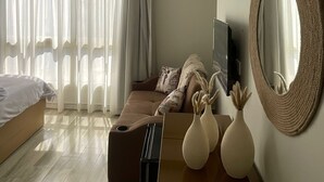 A modern hotel room with a bed, a sofa, a TV, and a large mirror. - Diyar Pyramids Inn (Giza)