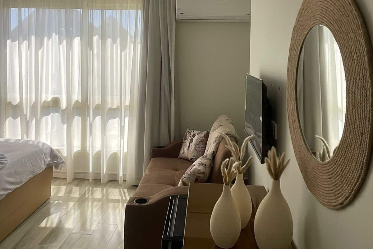 Habitació d'hotel moderna amb un llit, un sofà, una televisió i un mirall gran.