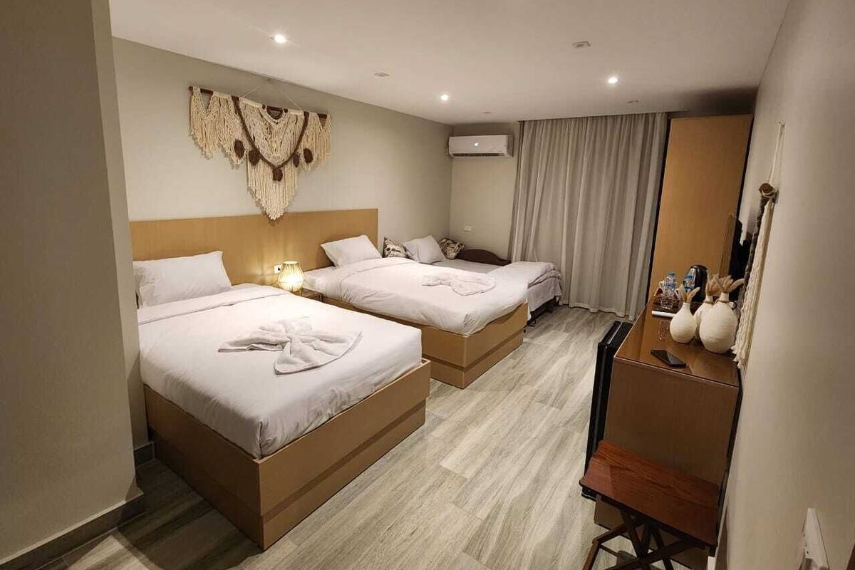 Habitació d'hotel amb dos llits, un escriptori, una cadira, un mirall i un aparell d'aire condicionat.