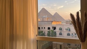 A view of the pyramids from a hotel balcony with a curtain partially drawn. - Diyar Pyramids Inn (Giza)