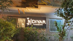 A sign for 'DIYAR Pyramids Inn' with a modern design, surrounded by greenery and architectural details. - Diyar Pyramids Inn (Giza)