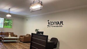 A reception area with a reception desk, two sofas, a coffee table, and a chandelier. - Diyar Pyramids Inn (Giza)