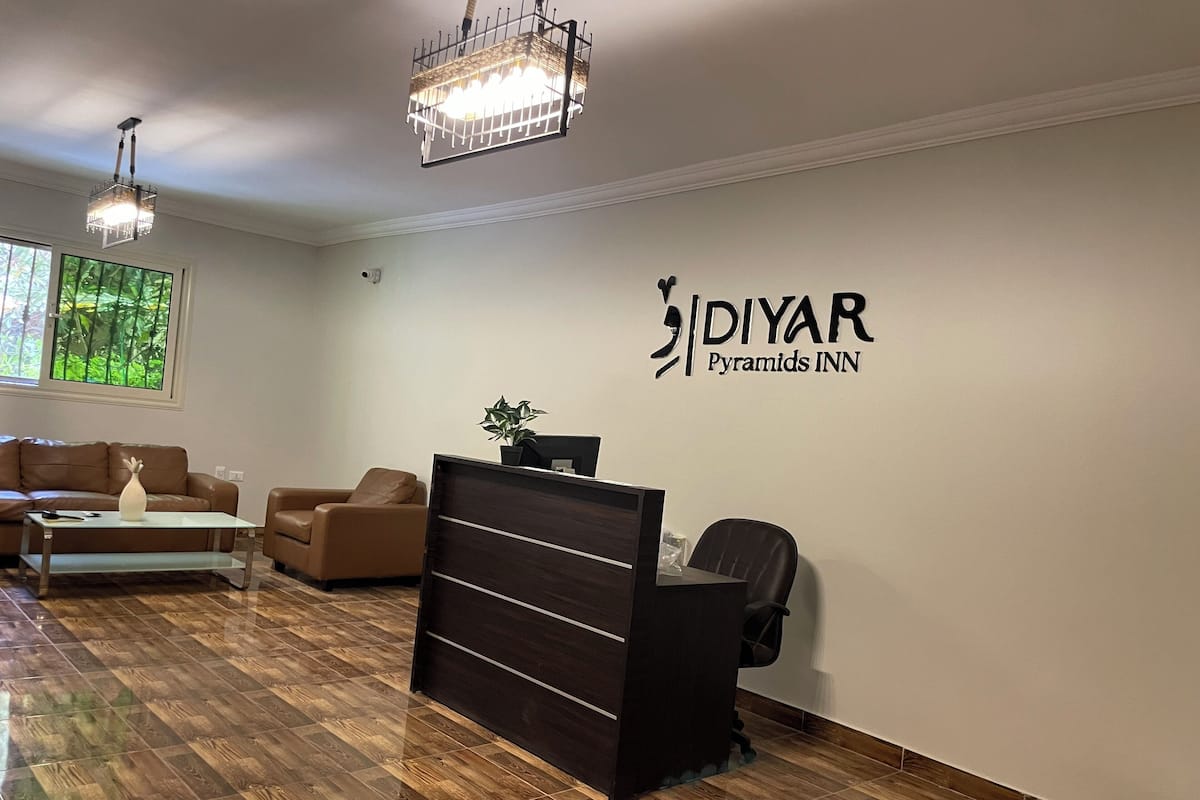 Una zona d'entrada amb una recepció, dos sofàs, una taula de cafè i una pèndol.